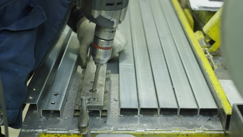 Close-up of heavy metal work. A man makes holes with a drill. High quality 4k footage 
