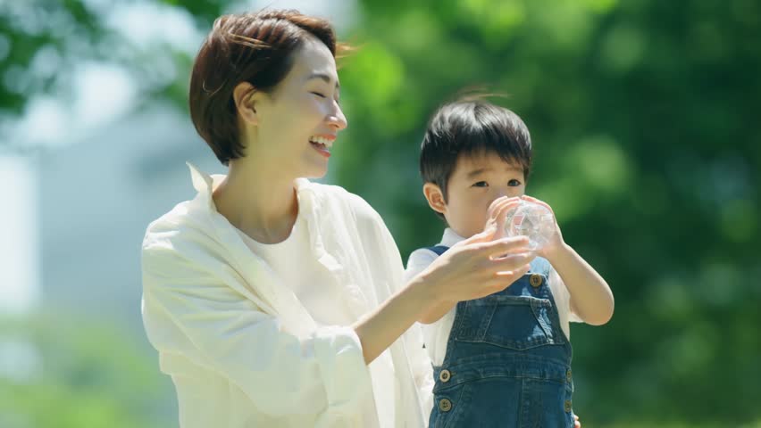 A mother lets her 3-year-old son drink water