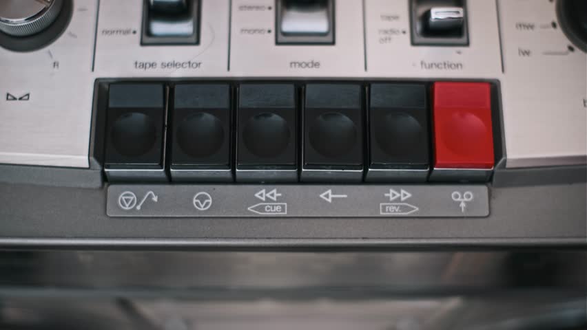 A finger presses the play button on a vintage cassette tape deck. Close up shot on an old recorder, perfect for retro, music, and technology projects.