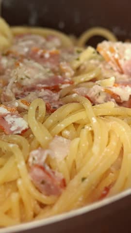 Close up of carbanara paste is sprinkled with grated parmesan cheese. Spaghetti. Cooking Food. Italian Cuisine. Vertical shot