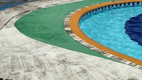 A vibrant colored swimming pool of a vintage motel resort with clear blue water and a unique design with curved green and orange borders. Ideal for architecture, leisure, and outdoor design themes. - Powered by Shutterstock - Get 15% off with code: PIKWIZARD15