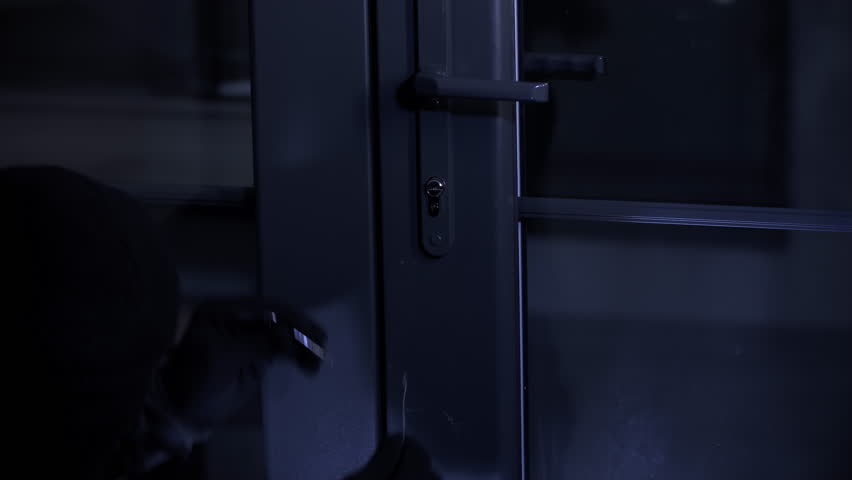 trespassing, theft male in balaclava with master key in hands opens door lock at night, close-up