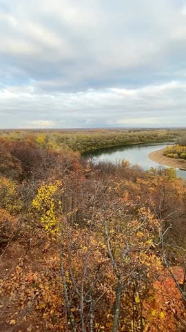 The autumn landscape features a winding river and colorful foliage under cloudy skies, creating a serene scene that invites exploration and appreciation of natures beauty