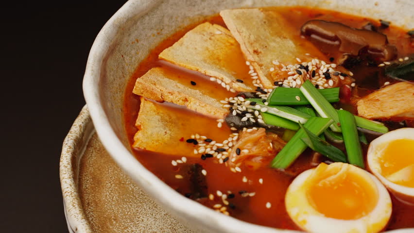 Japanese Ramen with beef or chicken, rice noodles with fried meat, Tom Yum rotates on the right background, close-up, vertical video. Spicy Thai Asian soup, chef cooks in traditional Korean Chinese cu