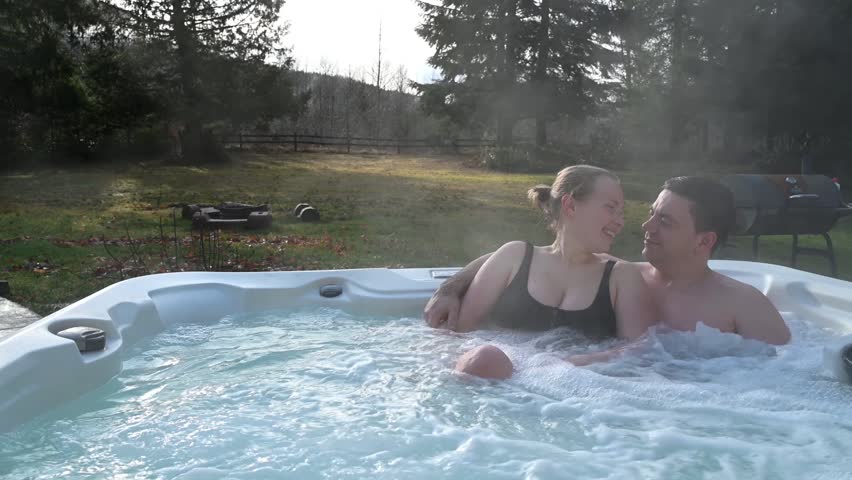 A couple in a hot jacuzzi shares tender moments in an atmosphere of tranquility. The photo is ideal for advertising vacations, resorts, or romantic tours.