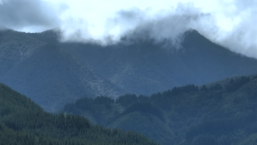 Drone Shot of White Clouds Covering Heavily Forested Mountain Range, Moody Landscape in New Zealand