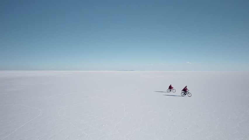 Couple Biking Across a Stunning Landscape in the Salt Flats - Salar de Uyuni, Bolivia