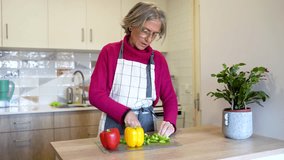 Senior woman cutting bell peppers in modern kitchen - Powered by Shutterstock - Get 15% off with code: PIKWIZARD15