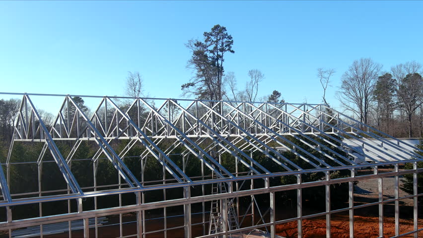 Workers are constructing sturdy it steel beams frame for new structure surrounded by metal warehouse