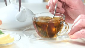  elderly man, holding a cup of hot tea, during breakfast, on the table, mixing the drink with a spoon, with dessert and fruit. Slow motion. - Powered by Shutterstock - Get 15% off with code: PIKWIZARD15