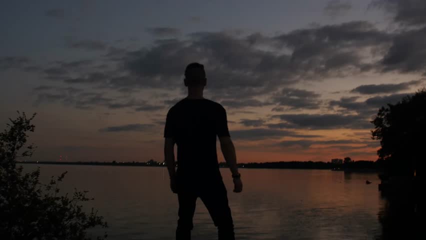 The shadow of a man is contemplating and looking into the lake at sunset. Lake Ontario, Canada.