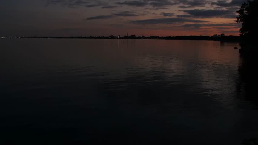 The shadow of a man is contemplating and looking into the lake at sunset. Lake Ontario, Canada.