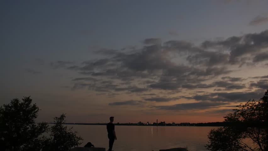 The shadow of a man is contemplating and looking into the lake at sunset. Lake Ontario, Canada.