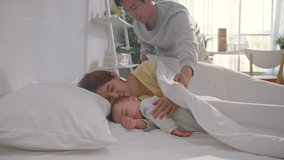 Asian father put blanket on his wife and sleeping baby boy with gently. Attractive parents look after young son infant toddler lying down and resting comfortably, sleep for early childhood development - Powered by Shutterstock - Get 15% off with code: PIKWIZARD15