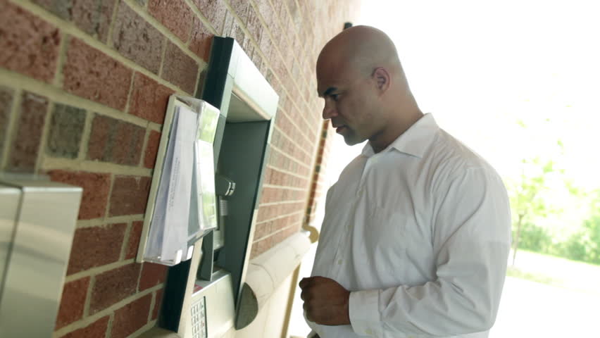 Man uses ATM then exits frame. Camera mounted on slider.