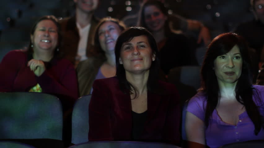 Various adults watching a movie and clapping. Jib movement and projections on