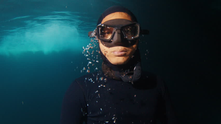 Close up freediver portrait exploring dark underwater cave and coming to surface