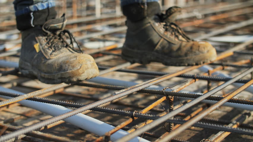 Worker tying steel reinforcement bars at construction site
