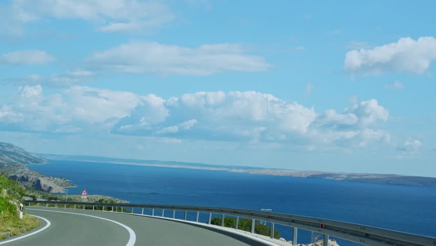 Breathtaking coastal road view with the Adriatic Sea and majestic mountains in the background, captured from a moving car in Croatia. Scenic travel, summer adventure, and exploring nature beauty. 