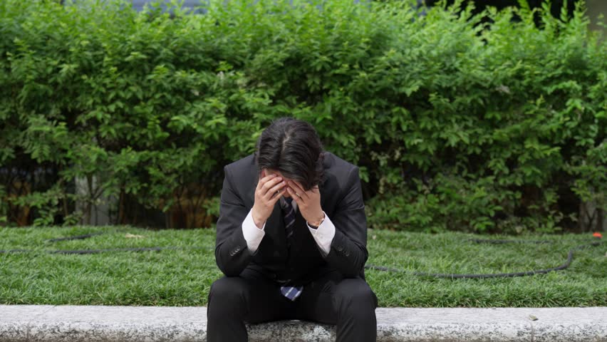 Businessman holding his head outside
