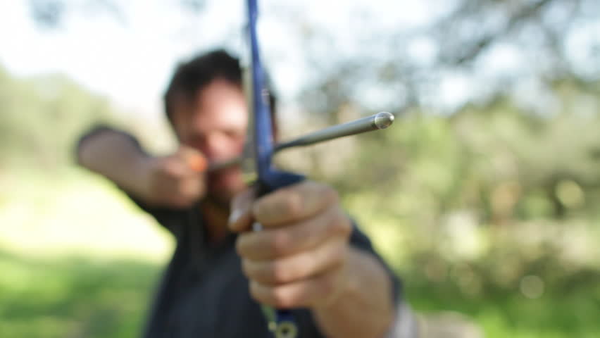 Archer viewed from the front with extremely shallow focus just on the arrow tip.