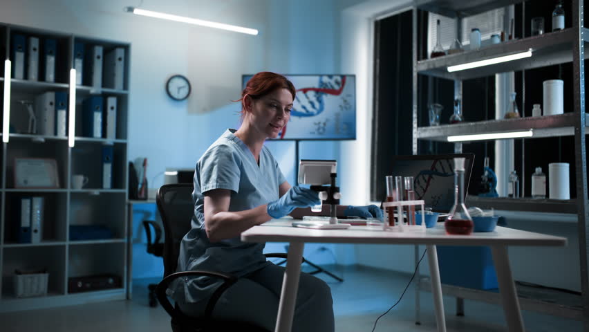 modern medicine, young female medical worker wearing protective gloves conducts laboratory research using microscope and test tubes with chemicals sitting in hospital office - Powered by Shutterstock - Get 15% off with code: PIKWIZARD15