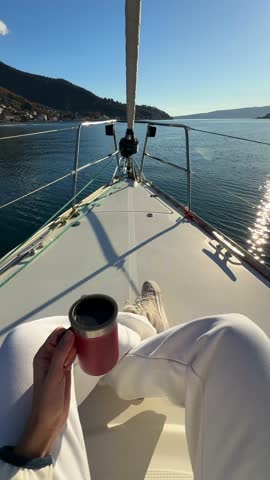 Woman hands holding thermo mug sitting on bow of the yacht during sailing in the morning in winter time in Adriatic sea, relaxation in yachting time. High quality 4k footage