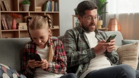 Caucasian Internet addicted male dad guy man kid daughter family using mobile phone smartphone dependency at home sofa little girl child parent father playing digital game online family technology app - Powered by Shutterstock - Get 15% off with code: PIKWIZARD15