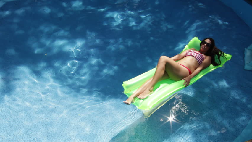 Beautiful woman sunbathing on a floating mattress, fades in and out on swimming