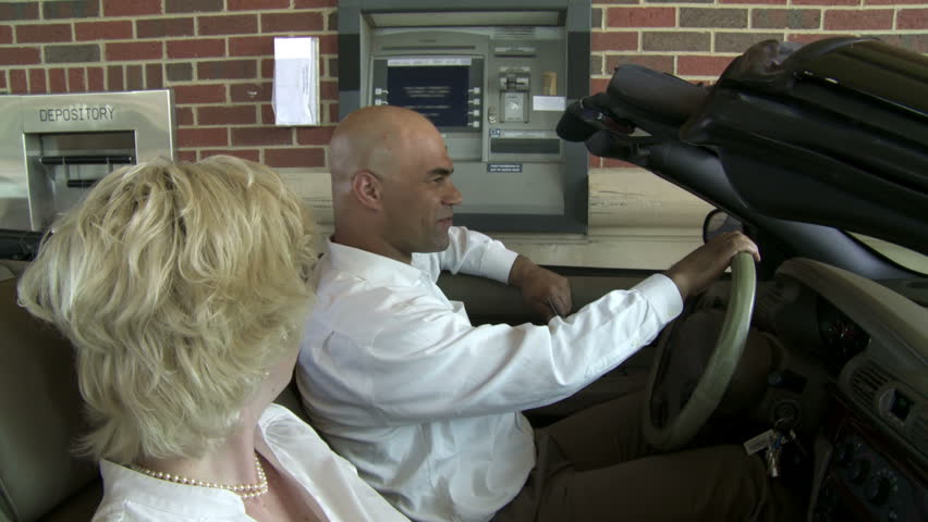 Couple in a convertible drive up to use an ATM. Camera mounted on jib.
