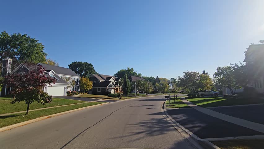 Suburban Street with Trees, A quiet residential street lined with trees and houses under a clear sky USA Illinois