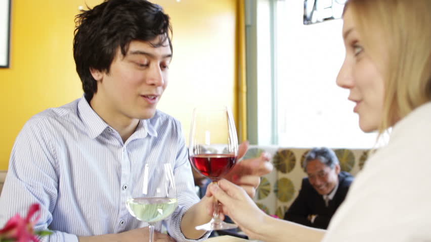 Young woman teases male companion with a glass of red wine in a restaurant, ends
