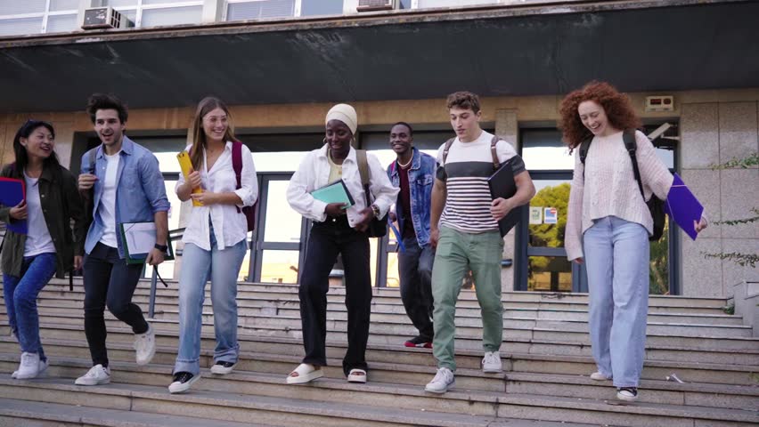 Cheerful group of multiethnic students running going out of university. Concept of last day of school.