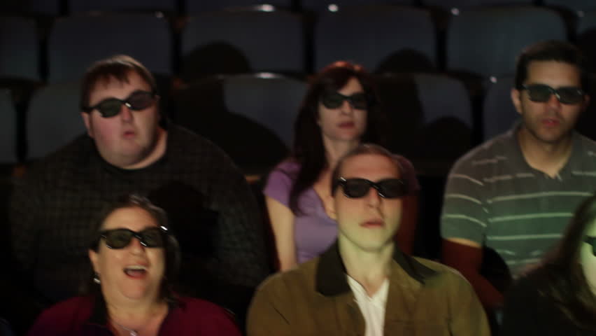Audience reaction with emphasis on man at 3D movie screening. Camera moves on a