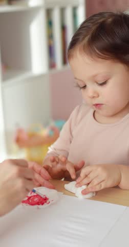 Cute child girl with mother painting at home, education concept.