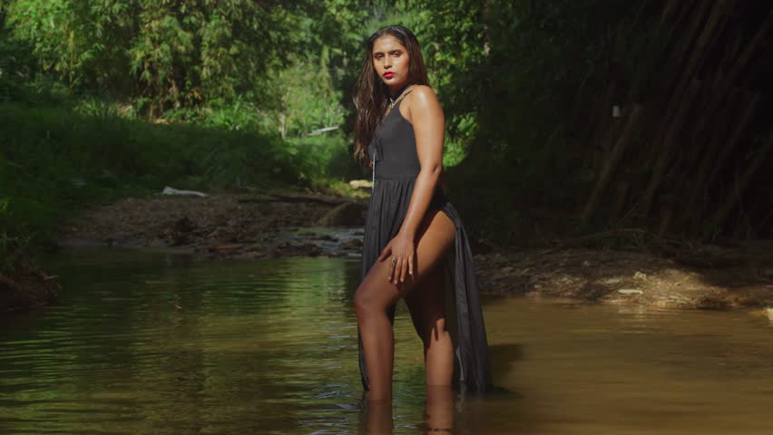 A girl in a flowing black dress basks in the river