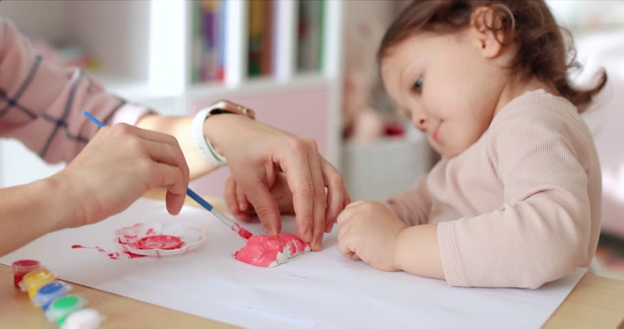 cute little child girl with mother painting toy gypsum figure in pink. creativity. Handmade toy