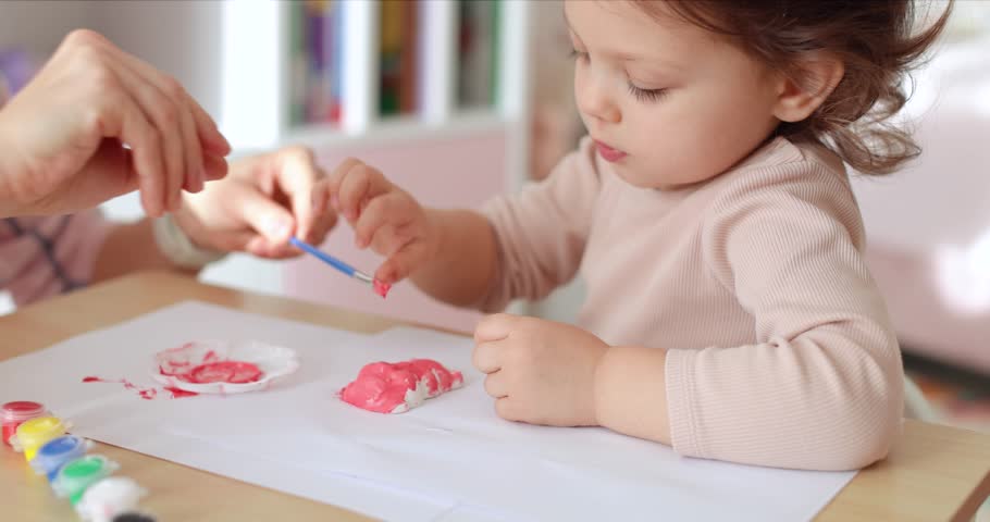 cute little child girl with mother painting toy gypsum figure in pink. creativity. Handmade toy