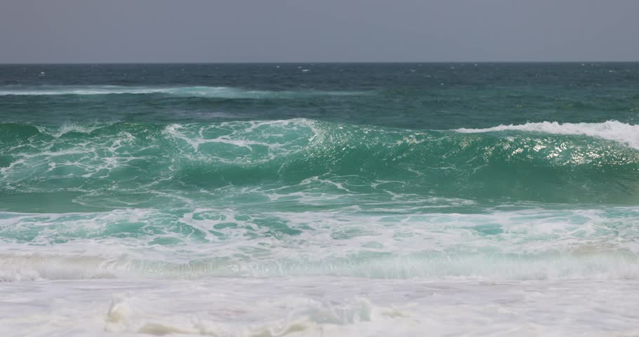 Powerful turquoise ocean waves crash on a sandy tropical beach in slow motion. Perfect for coastal, nature, and summer vacation themes, highlighting the beauty of the sea.