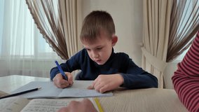 Boy at home writing in a copybook with a pen - doing homework with his mother - Powered by Shutterstock - Get 15% off with code: PIKWIZARD15