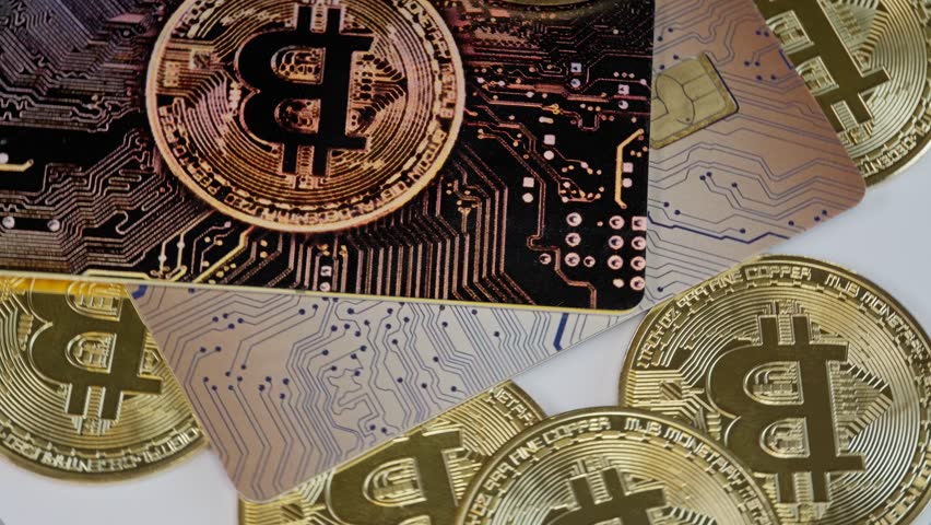 Bitcoin credit cards and coins rotate on a white surface, symbolizing cryptocurrency, decentralized finance, and digital payments