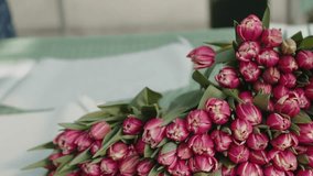  Arranging pink tulips into a bouquet on a table - Powered by Shutterstock - Get 15% off with code: PIKWIZARD15