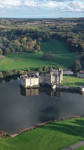 Leeds Castle With Dense Forest On A Sunny Day In Kent, England, UK. - aerial vertical shot