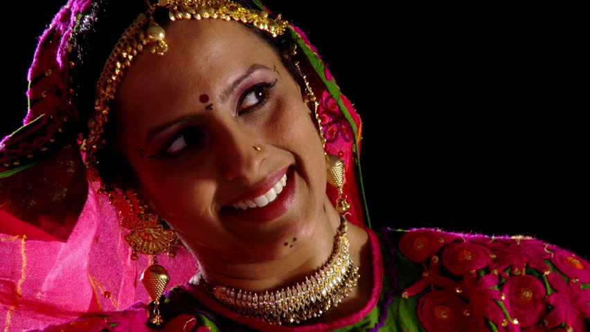 Indian girl in traditional dance costume reveals her face briefly, smiles at