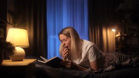 A happy young woman in spectacles lying on bed reading favourite interesting book at home in room lighted by lamp - Powered by Shutterstock - Get 15% off with code: PIKWIZARD15