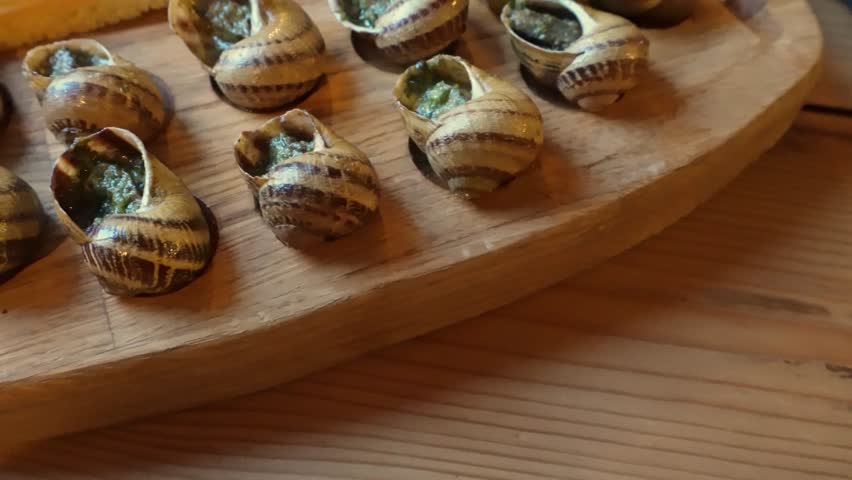Freshly prepared escargot with garlic butter on wooden board