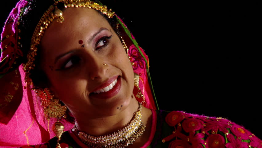 Indian girl in traditional dance costume reveals her face briefly and smiles at