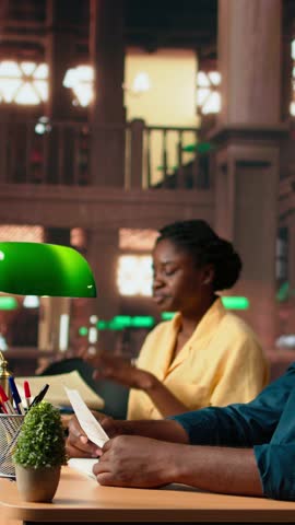 Vertical Video African american college student struggling to study theoretical notes from the last class lesson, learning to prepare for the exam. Anxious frustrated teenager at the campus library