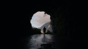 Aerial view of a silhouette of a man walking out of a mountain tunnel with breathtaking mountain landscape view of Madeira island, beautiful sunset view - Powered by Shutterstock - Get 15% off with code: PIKWIZARD15