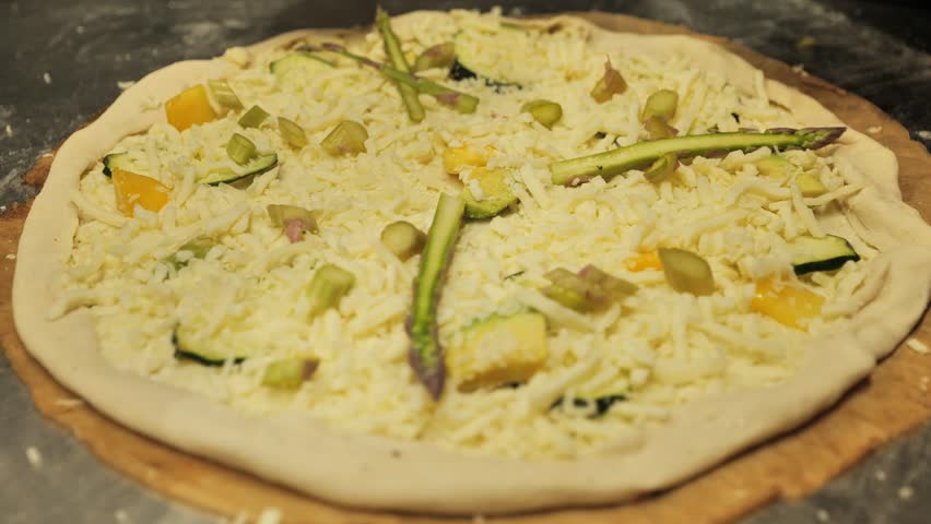 Chef preparing vegetarian pizza with fresh ingredients in a professional kitchen